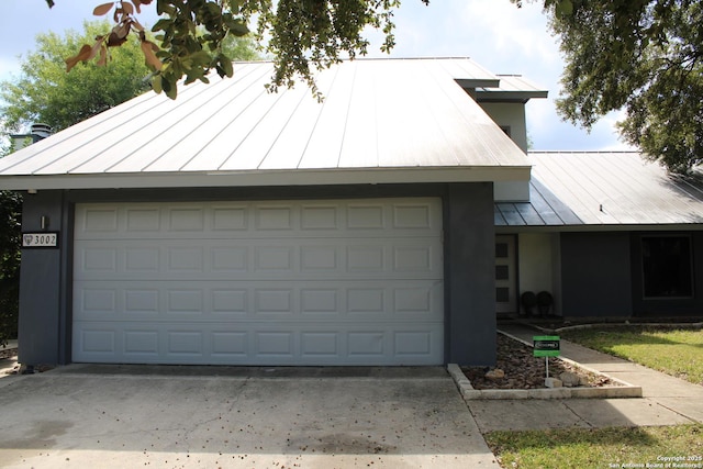 view of front of home with a standing seam roof, driveway, an attached garage, and metal roof