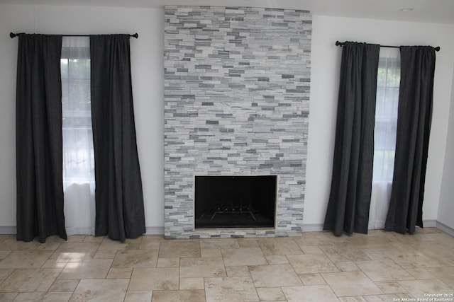 unfurnished living room featuring a fireplace and baseboards