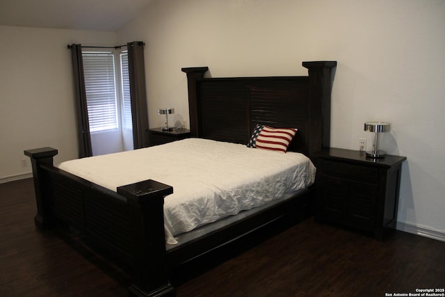 bedroom featuring dark wood-style floors, lofted ceiling, and baseboards