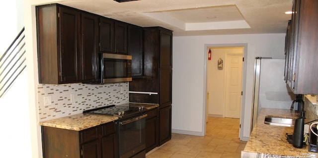 kitchen featuring electric range, decorative backsplash, a raised ceiling, stainless steel microwave, and a sink