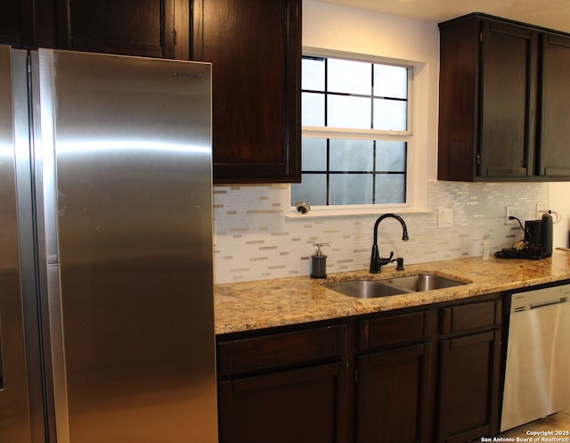 kitchen with stainless steel appliances, a sink, backsplash, and dark brown cabinets