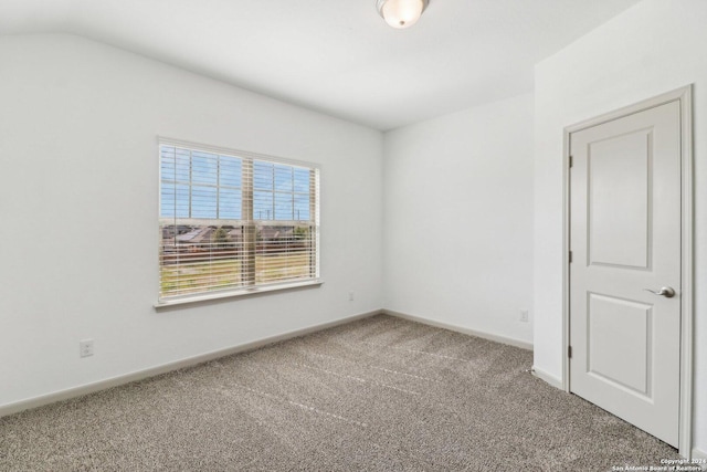empty room with carpet, lofted ceiling, and baseboards