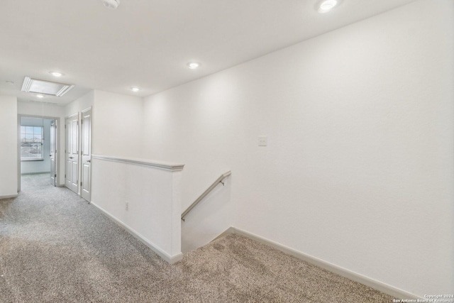 corridor with carpet floors, attic access, baseboards, and an upstairs landing
