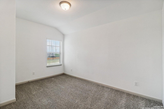 unfurnished room with carpet, baseboards, and vaulted ceiling