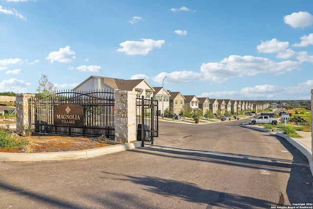 view of street with curbs, a gated entry, a gate, and a residential view