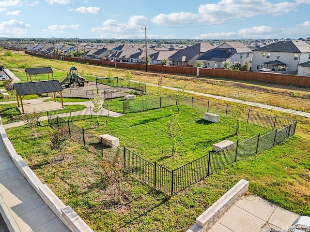 view of home's community with a residential view, playground community, a yard, and fence