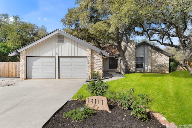 mid-century inspired home with a garage, driveway, stone siding, and a front yard