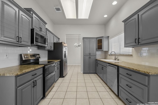 kitchen featuring stainless steel appliances, gray cabinets, visible vents, and a sink