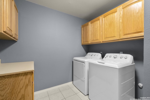 clothes washing area with baseboards, light tile patterned flooring, cabinet space, and washer and dryer