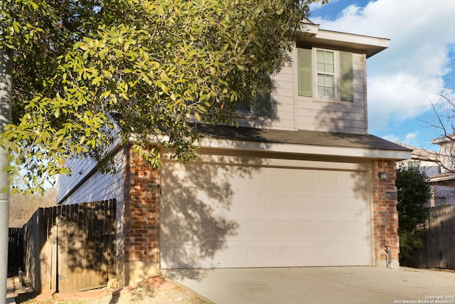 view of side of property featuring concrete driveway, brick siding, and fence