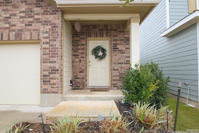 doorway to property featuring a garage and brick siding