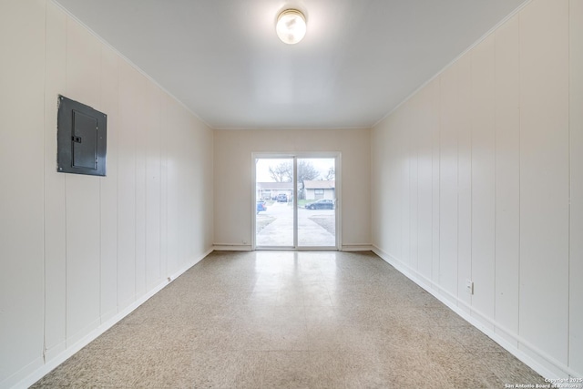 spare room featuring ornamental molding, speckled floor, electric panel, and baseboards