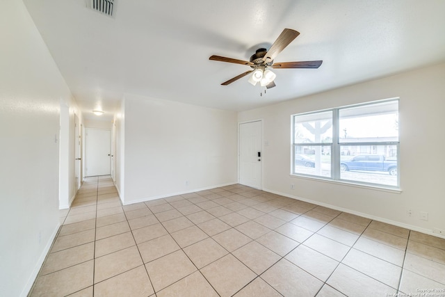 empty room with light tile patterned floors, ceiling fan, visible vents, and baseboards