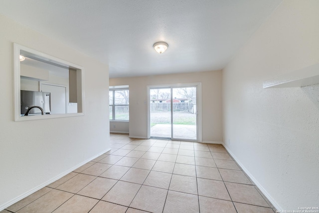 empty room featuring light tile patterned flooring and baseboards