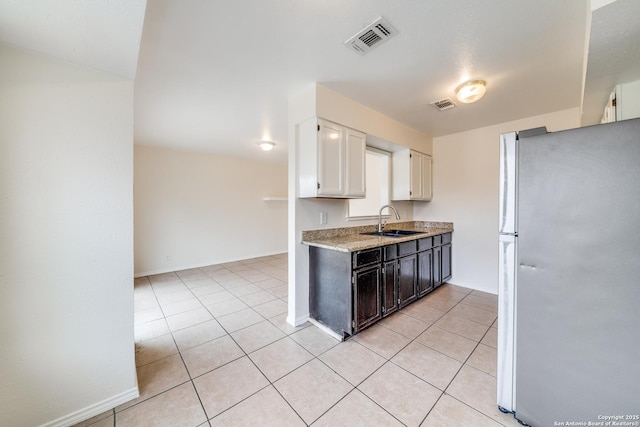 kitchen featuring light tile patterned floors, visible vents, a sink, and freestanding refrigerator