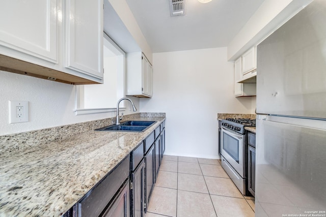 kitchen featuring visible vents, stainless steel appliances, under cabinet range hood, white cabinetry, and a sink