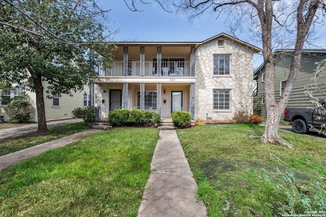 view of front of property with stone siding, a porch, a front lawn, and a balcony