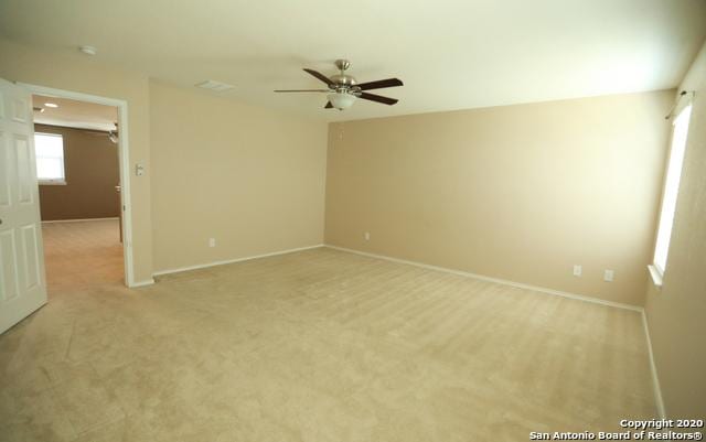 empty room featuring light carpet, ceiling fan, and baseboards