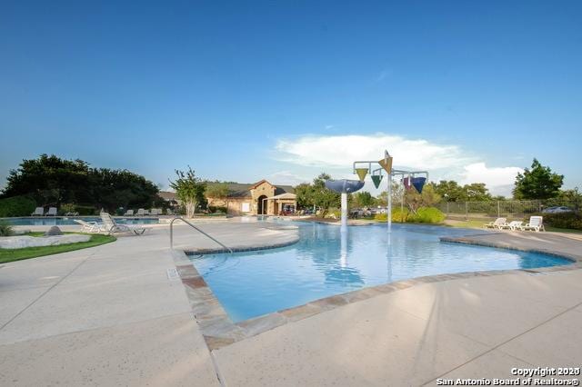 community pool with a patio area and fence