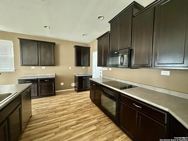 kitchen with a textured ceiling, baseboards, light wood-style floors, light countertops, and black appliances