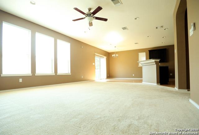 unfurnished living room with visible vents, light carpet, baseboards, and ceiling fan with notable chandelier