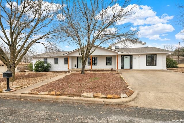 view of front of property with driveway, brick siding, and a shingled roof