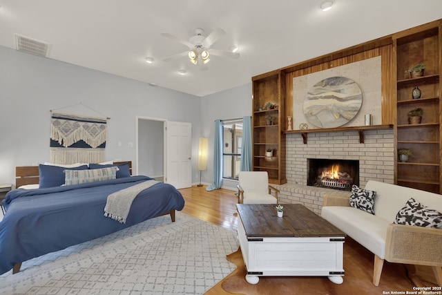 bedroom featuring a brick fireplace, wood finished floors, and visible vents