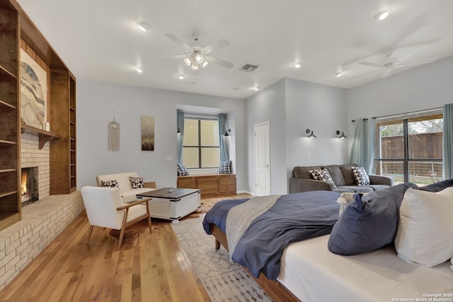 bedroom with recessed lighting, a ceiling fan, visible vents, light wood-style floors, and a brick fireplace