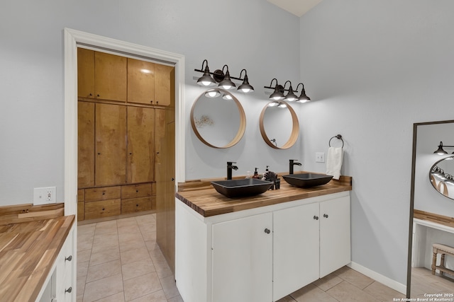 bathroom with double vanity, baseboards, a sink, and tile patterned floors