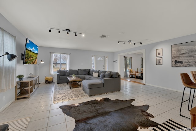 living room with rail lighting, light tile patterned flooring, visible vents, and baseboards