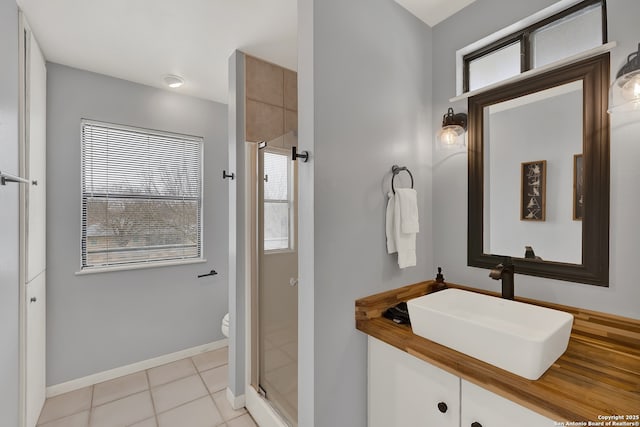 bathroom featuring tile patterned flooring, toilet, a shower stall, and baseboards