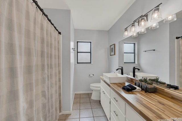 full bath with double vanity, baseboards, toilet, tile patterned flooring, and a sink