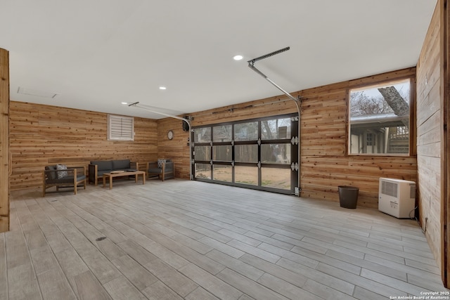 interior space with a garage, wood finished floors, and wooden walls