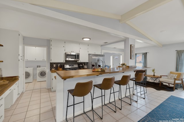 kitchen featuring appliances with stainless steel finishes, butcher block counters, decorative backsplash, and light tile patterned floors