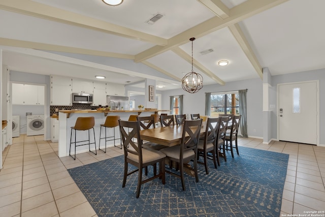 dining area featuring vaulted ceiling with beams, a notable chandelier, visible vents, washing machine and dryer, and light tile patterned flooring