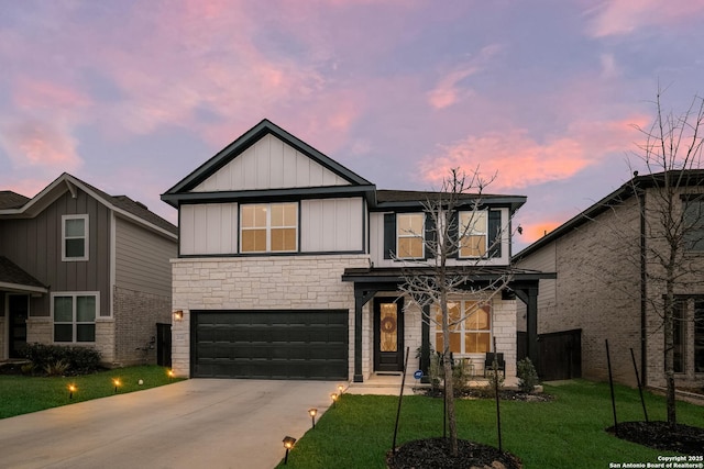 view of front of house featuring a yard, concrete driveway, an attached garage, board and batten siding, and stone siding