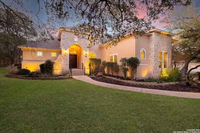 mediterranean / spanish-style home featuring stone siding, a lawn, and stucco siding