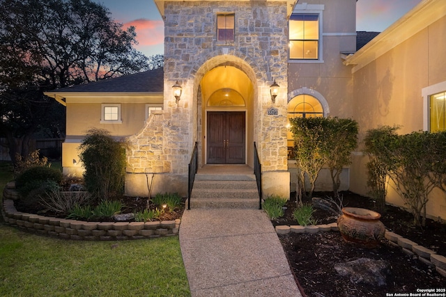 property entrance with stone siding and stucco siding