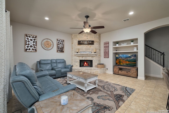 living area with built in shelves, arched walkways, a fireplace, visible vents, and stairs