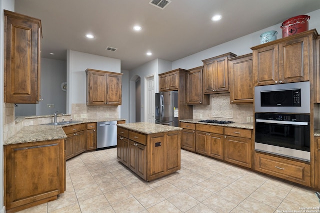 kitchen featuring arched walkways, light stone counters, a sink, visible vents, and appliances with stainless steel finishes