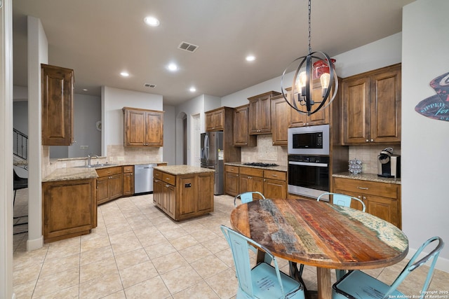 kitchen featuring visible vents, arched walkways, appliances with stainless steel finishes, a center island, and a sink