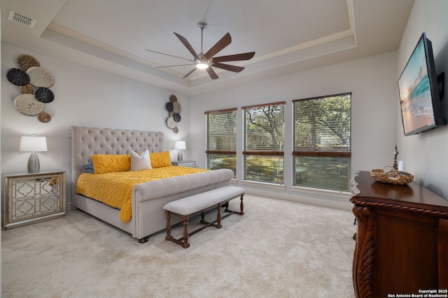 bedroom featuring a ceiling fan, a tray ceiling, carpet flooring, and visible vents