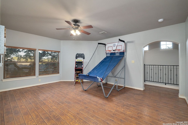 living area featuring arched walkways, visible vents, a ceiling fan, baseboards, and hardwood / wood-style floors