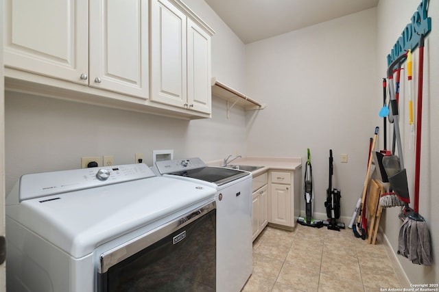 washroom with cabinet space, light tile patterned floors, baseboards, washer and clothes dryer, and a sink