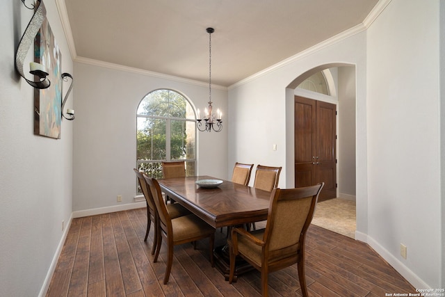 dining space with dark wood-style floors, crown molding, arched walkways, and baseboards