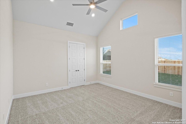 carpeted empty room featuring high vaulted ceiling, visible vents, ceiling fan, and baseboards