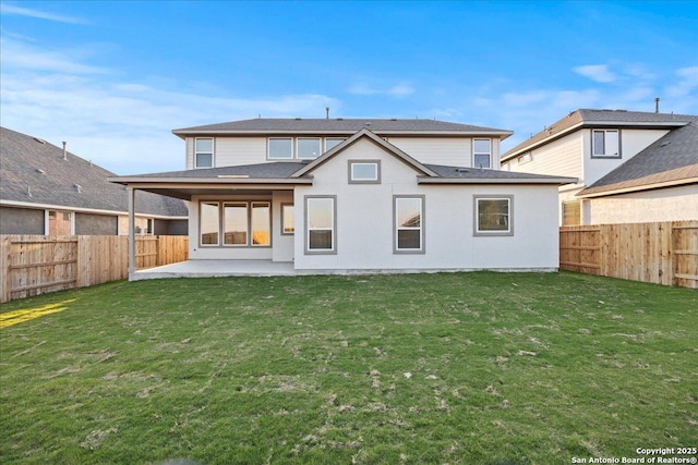 rear view of property featuring a fenced backyard, a lawn, and a patio