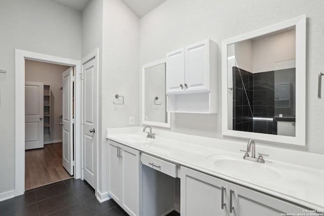 bathroom with double vanity, a sink, a tile shower, and tile patterned floors