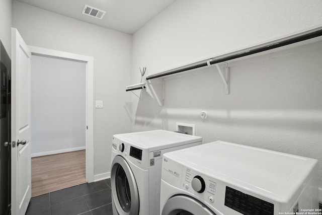 laundry area featuring laundry area, baseboards, visible vents, dark tile patterned flooring, and washing machine and clothes dryer