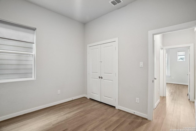 unfurnished bedroom with baseboards, a closet, visible vents, and wood finished floors